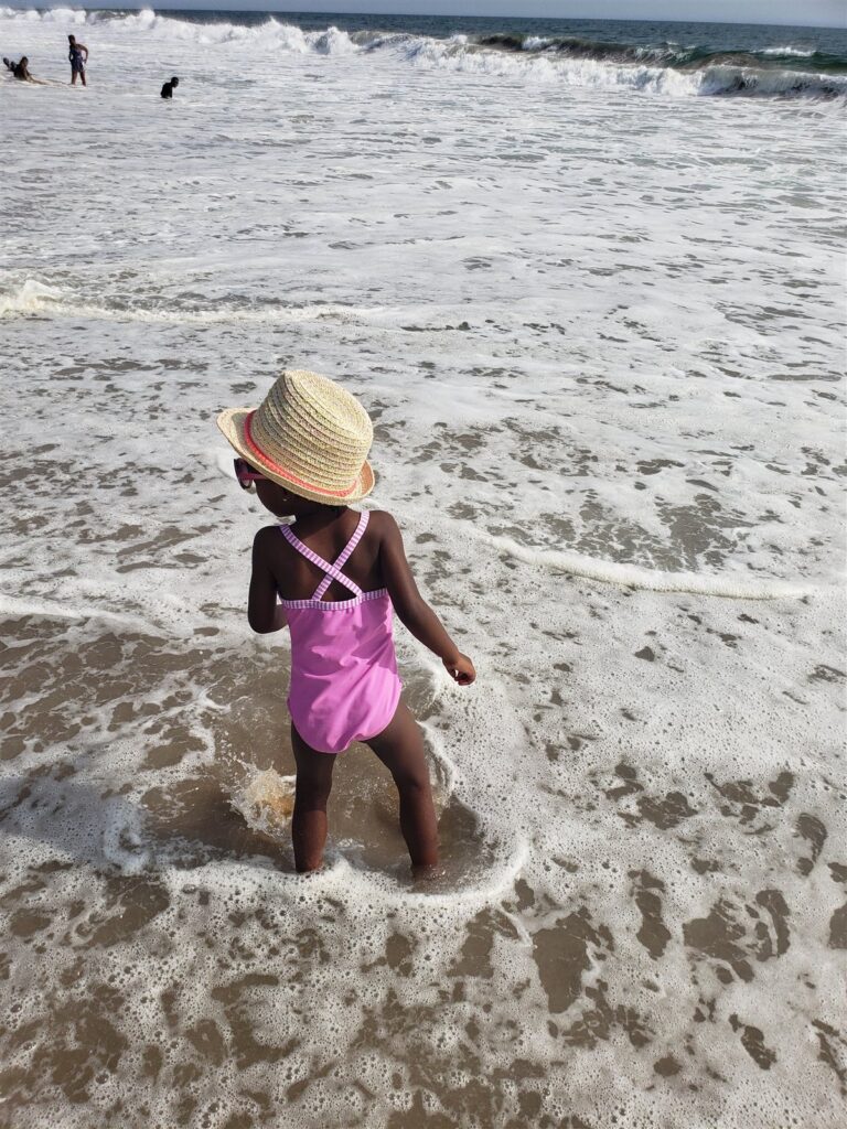 My daughter from behind in a straw hat at the water's edge in Grand-Bassam, Côte d'Ivoire
