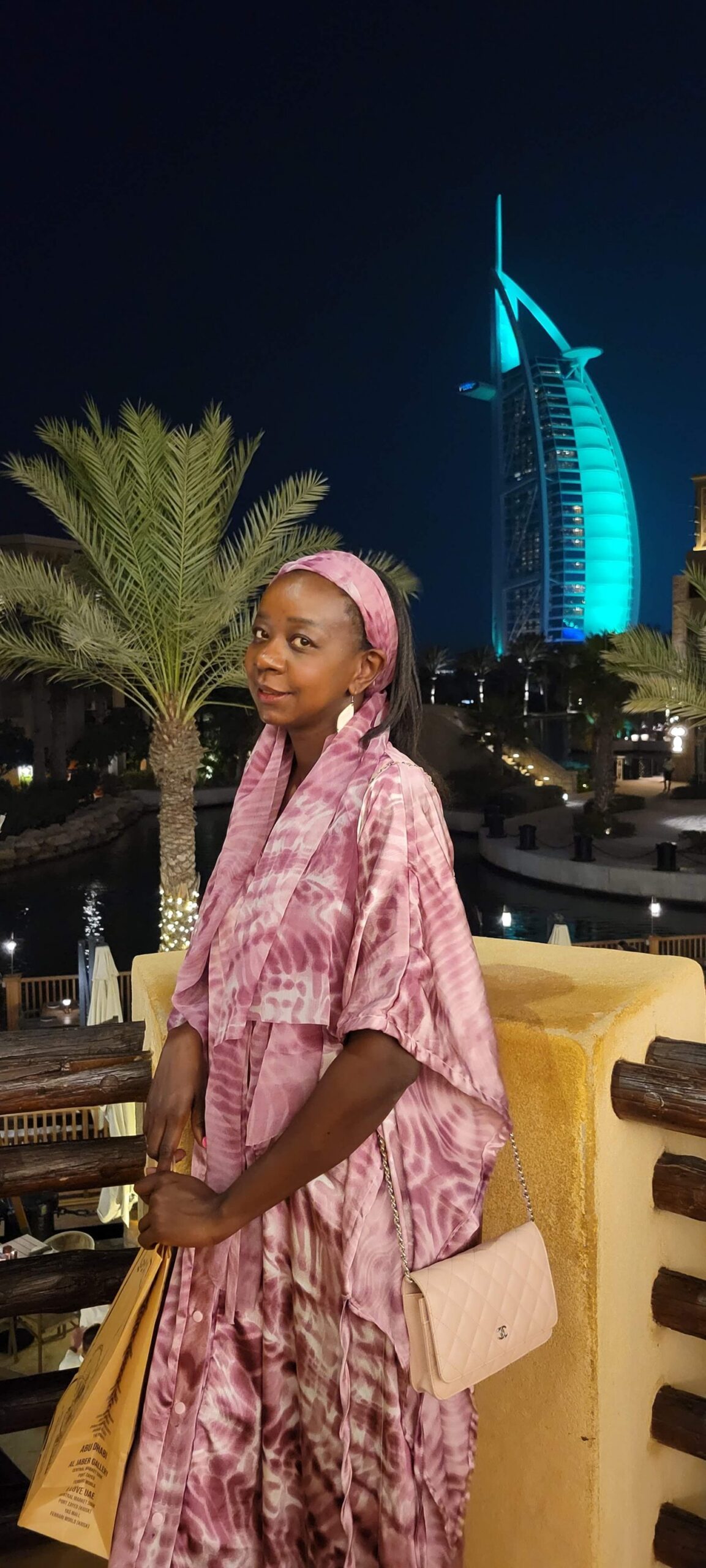 Samira in Dubai at night with the Burj Al Arab behind her